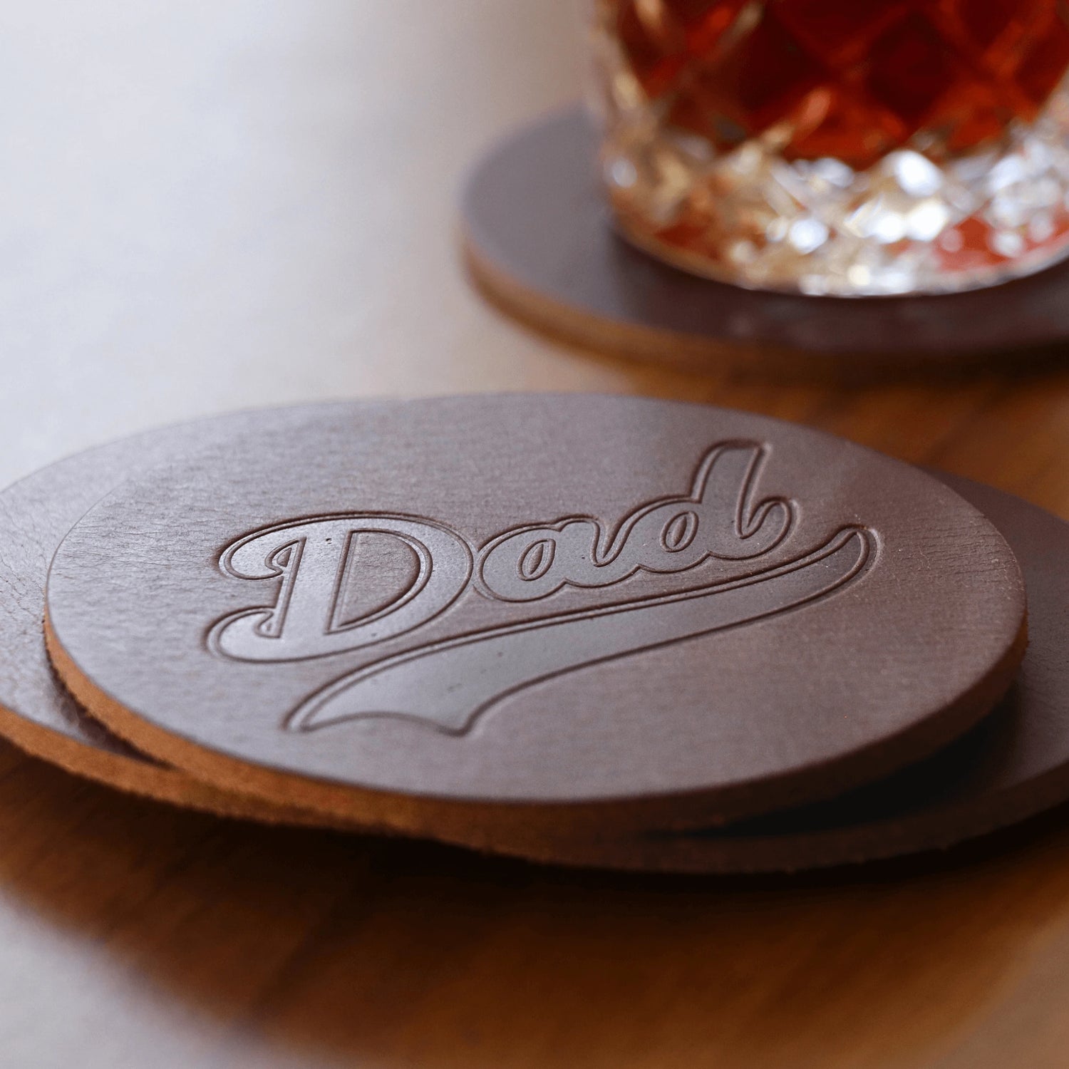 Leather coasters with 'Dad' embossing on a wooden surface