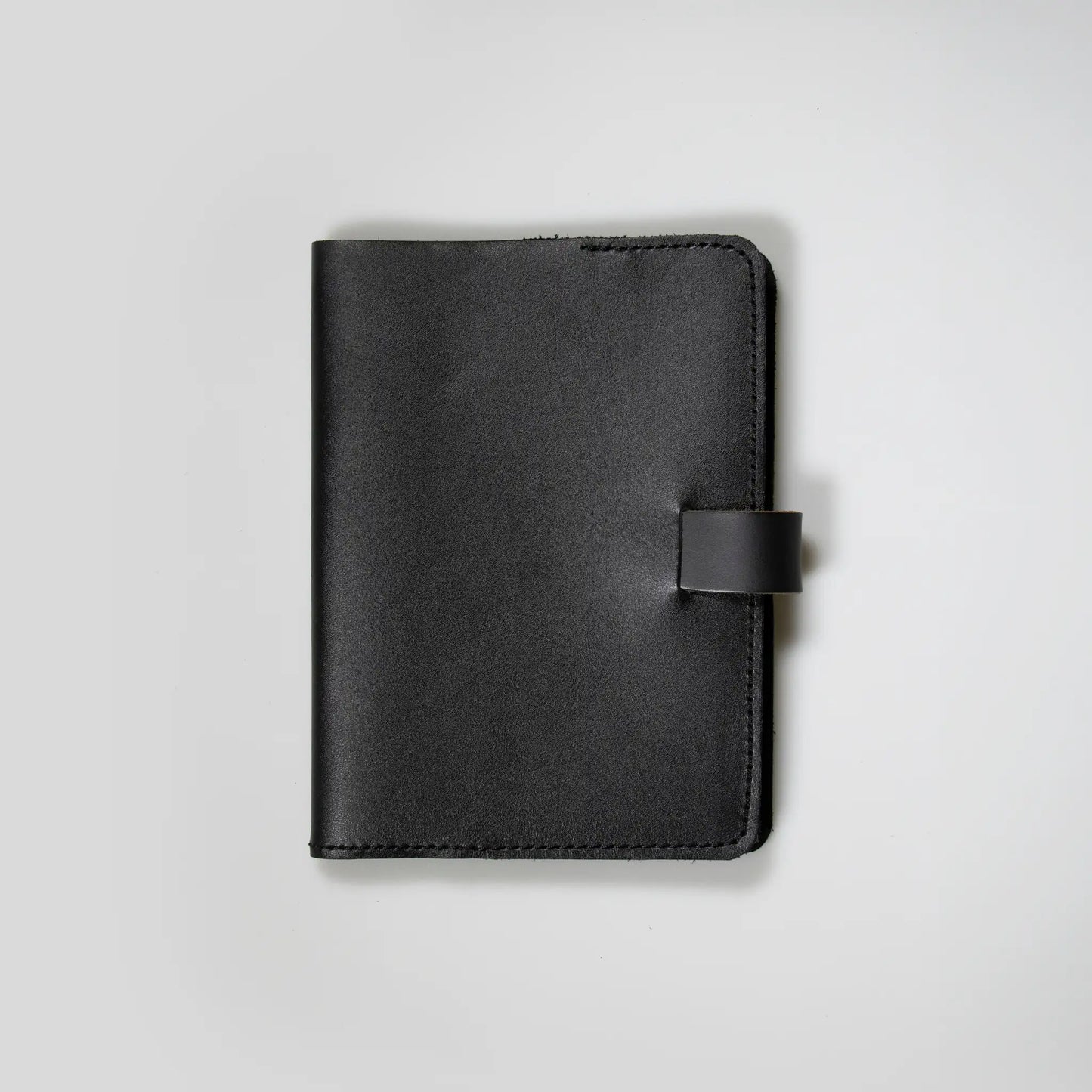 Minimalist black leather notebook showcasing quality New Zealand craftsmanship. Small batch design with tab closure and refined stitching—made to last, perfect men’s gift with vintage appeal.