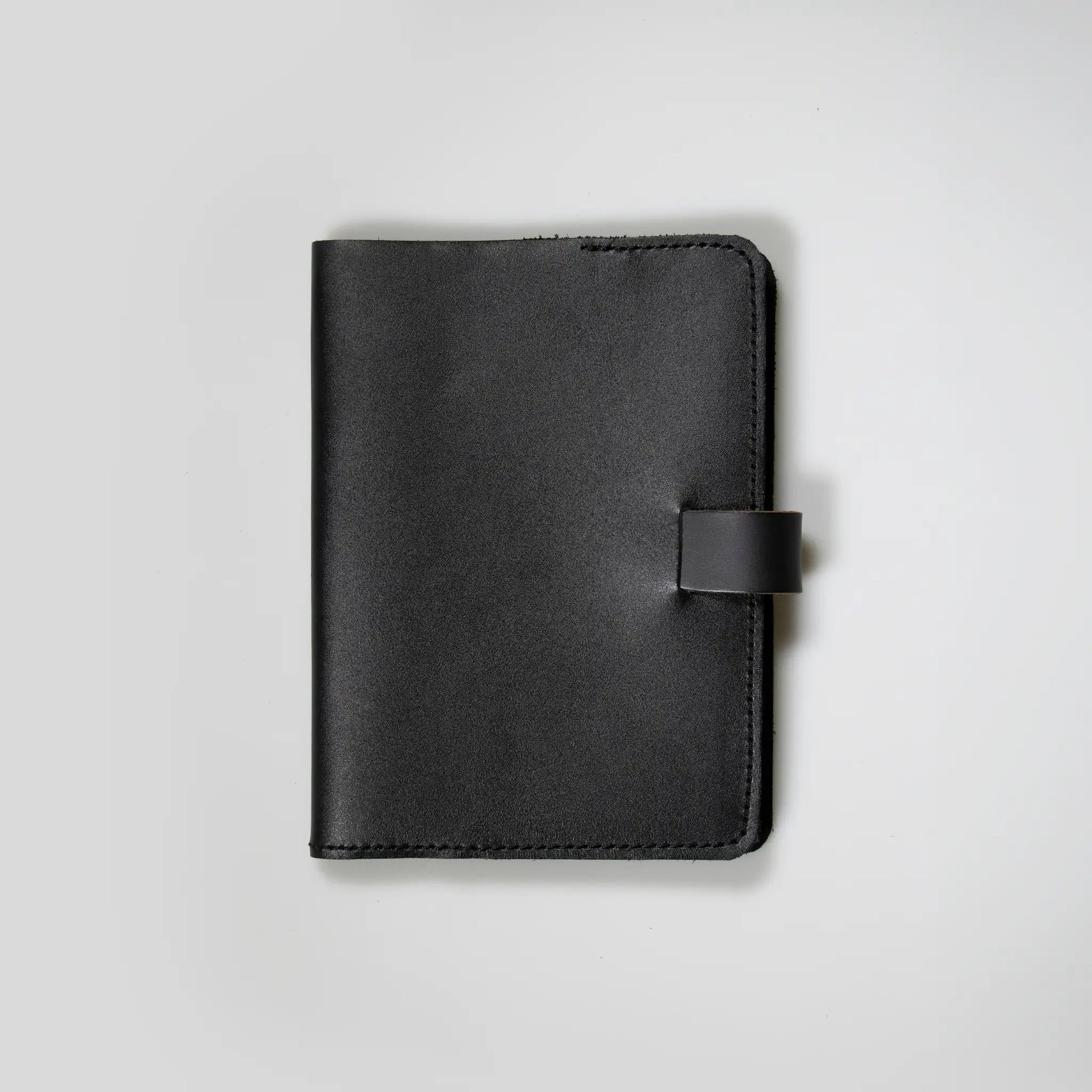 Minimalist black leather notebook showcasing quality New Zealand craftsmanship. Small batch design with tab closure and refined stitching—made to last, perfect men’s gift with vintage appeal.