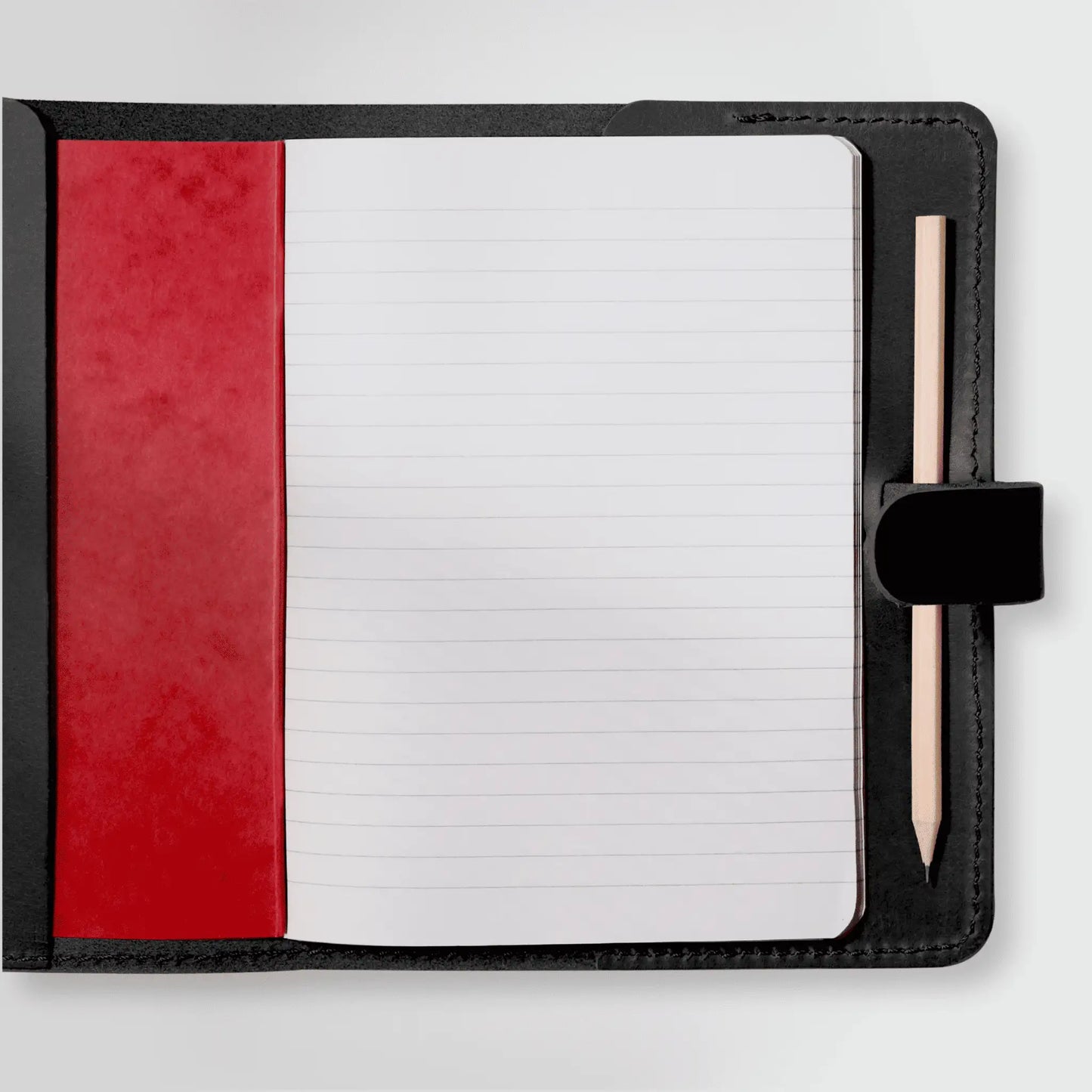 Open black leather A5 notebook showcasing red interior cover and pencil holder. New Zealand-made with everyday simplicity in mind.