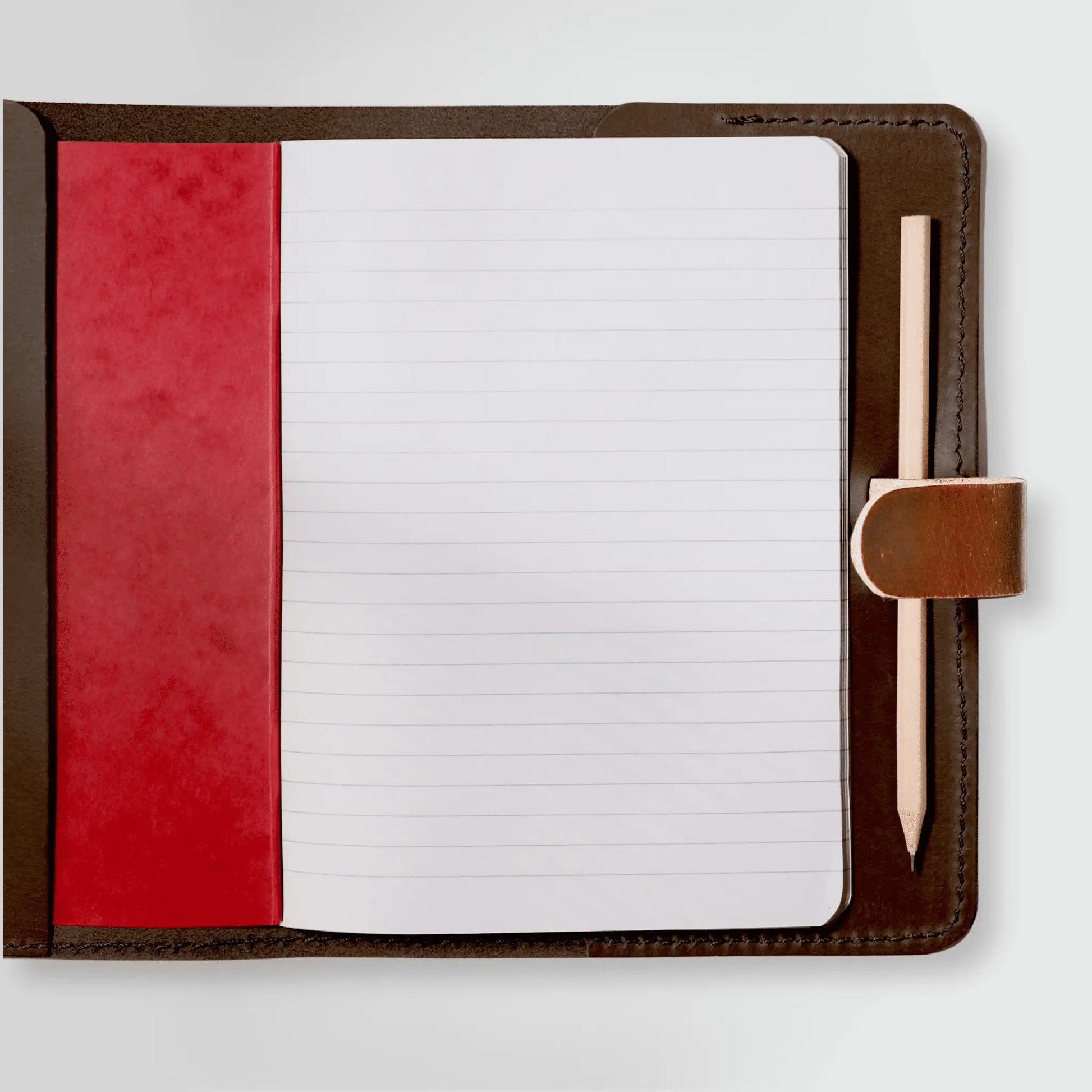 Inside of genuine leather notebook showcasing quality craftsmanship with lined paper, pencil holder, and red interior cover. New Zealand-made in timeless tan leather.