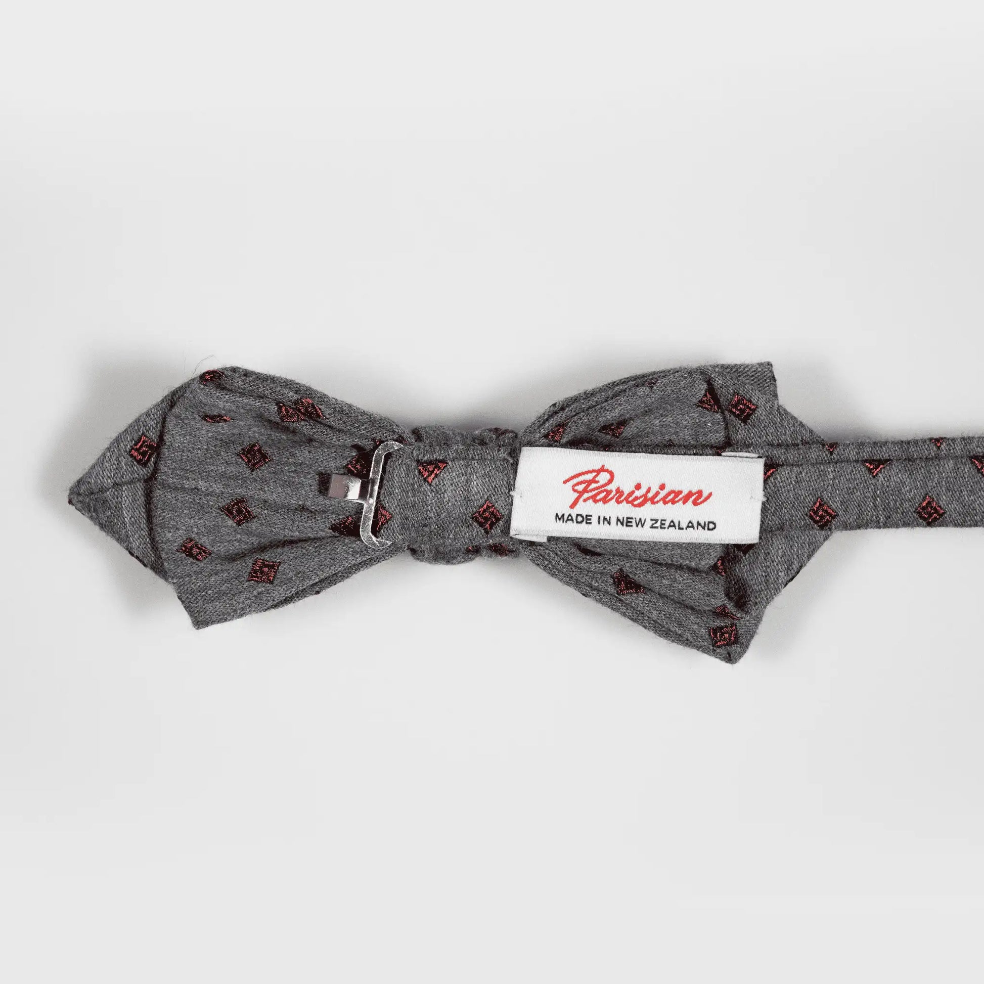 Back of Grey bow tie with burgundy diamond pattern, displaying 'Parisian Made in New Zealand' woven label—quality men's accessory  for simple styling.