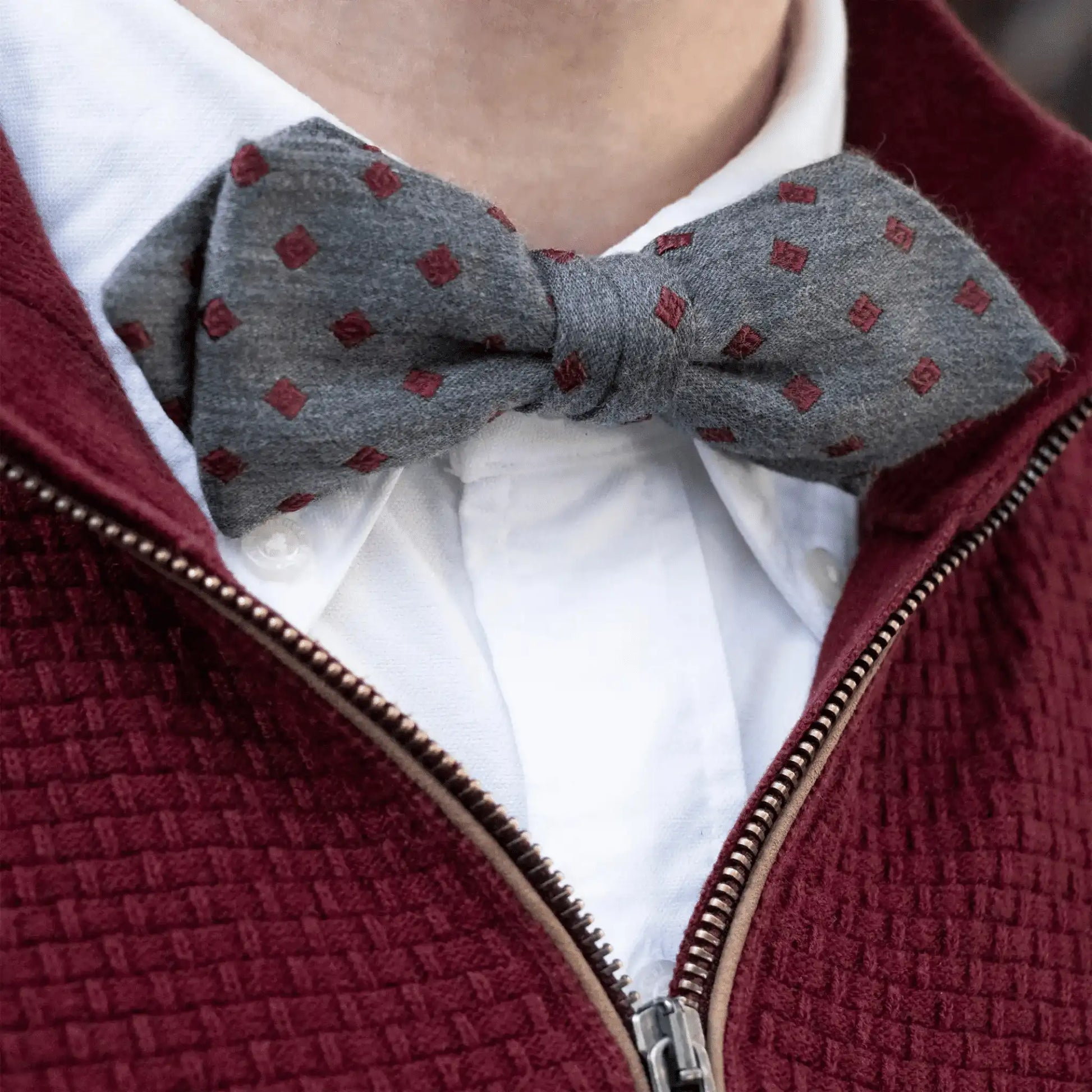 Grey marle bow tie with burgundy diamond pattern, styled with a white button-down shirt and burgundy woven zip-up jumper—New Zealand men's accessory.