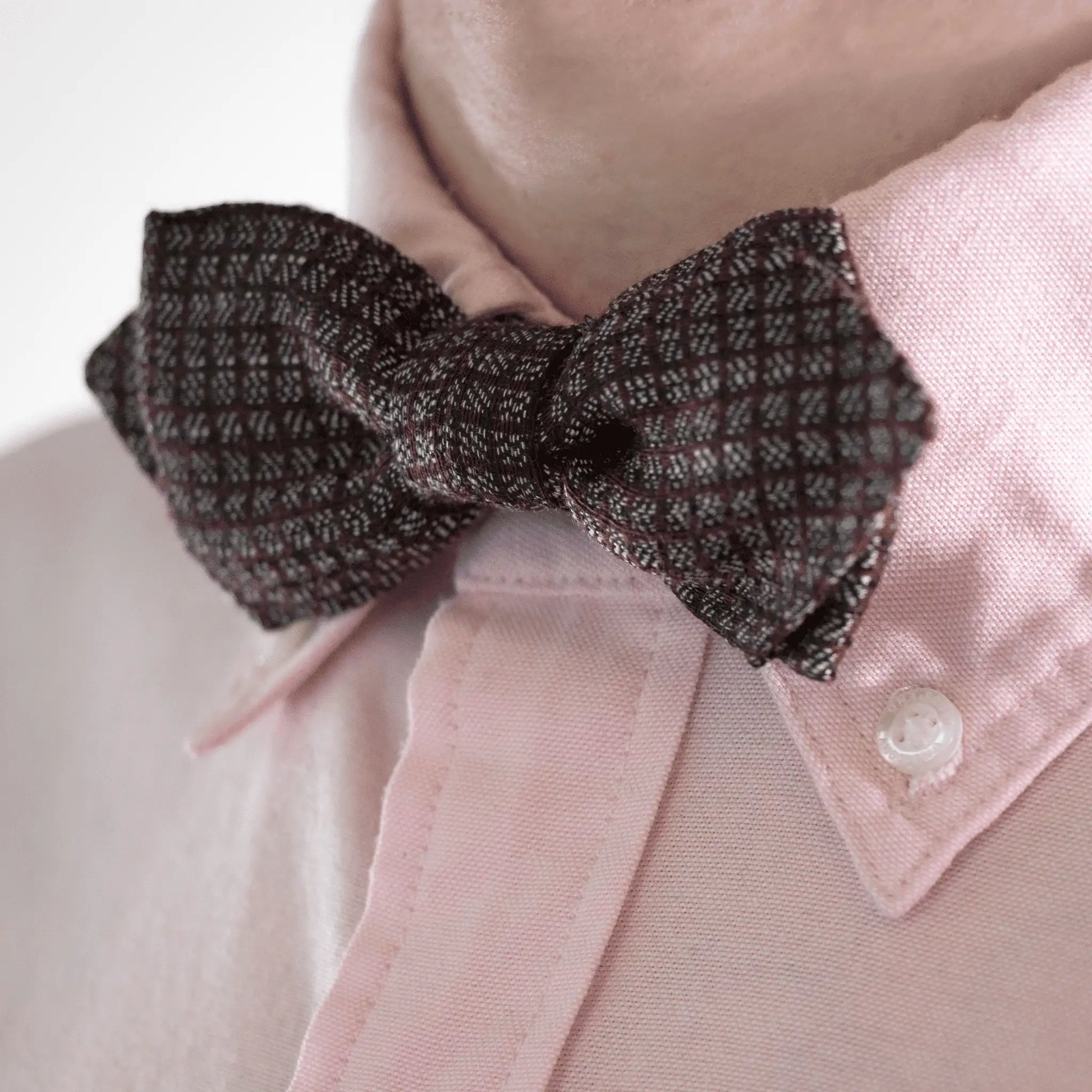 Close-up of Burgundy Grey Micro Squares Bow Tie worn with a pink button-down shirt, showcasing its simple design and sophisticated style.