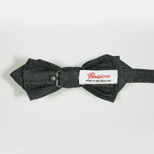 'Parisian Made in New Zealand' woven label shown on the back of an olive green and navy blue Jacquard pattern bow tie.