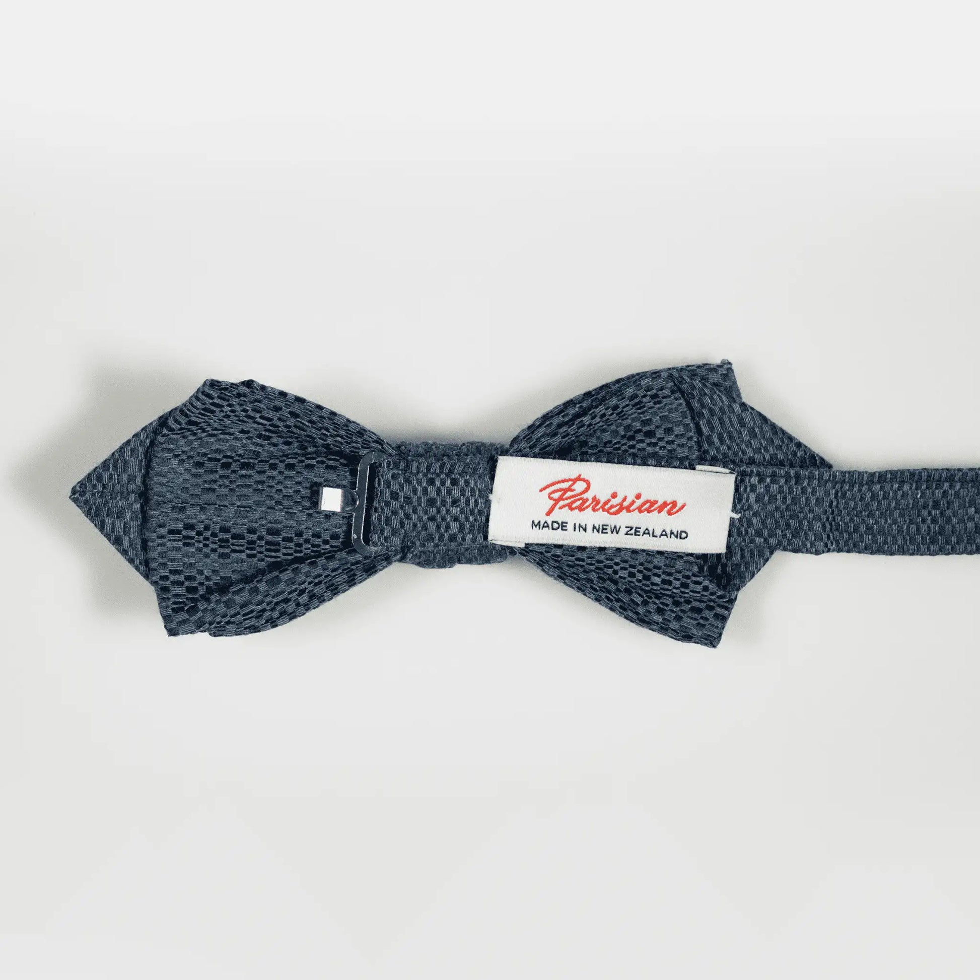 Back of slate blue Jacquard pattern bow tie, showing 'Parisian Made in New Zealand' woven label, emphasising refined design and materials.