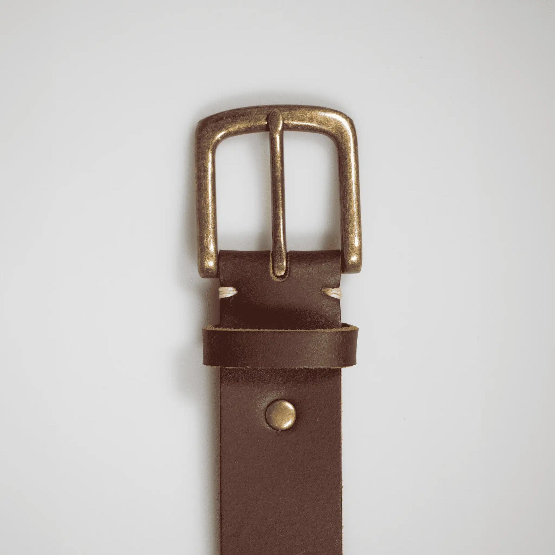 Close-up of simple brass buckle on a rustic brown genuine leather men's belt. Crafted in New Zealand and perfect for gifting.
