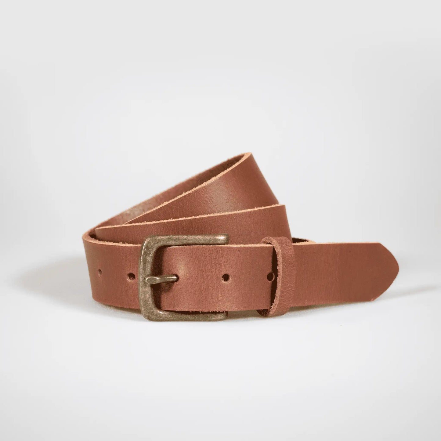 Tan leather belt, rolled up on white surface—designed with everyday wear in mind for a timeless menswear style.