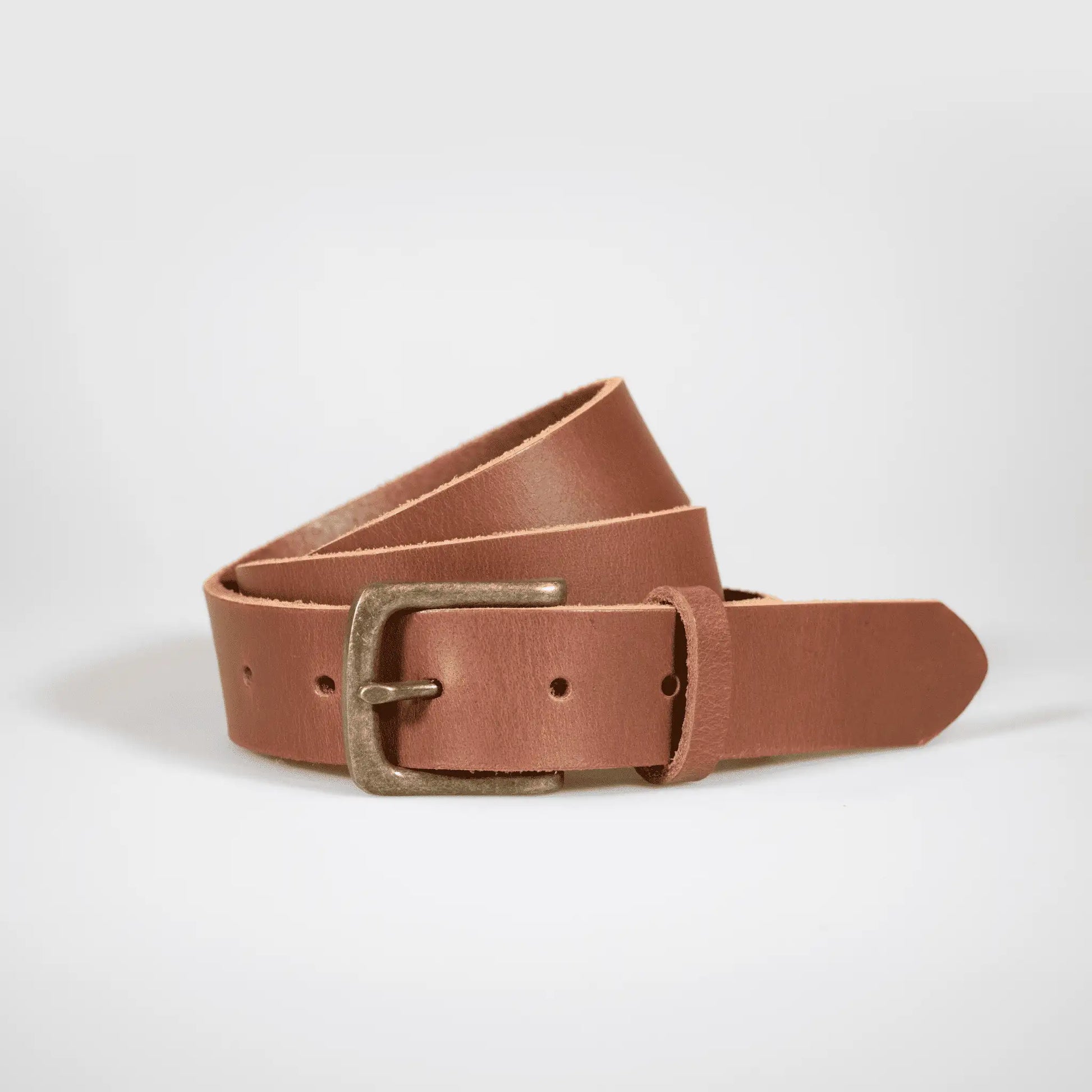 Tan leather belt, rolled up on white surface—designed with everyday wear in mind for a timeless menswear style.