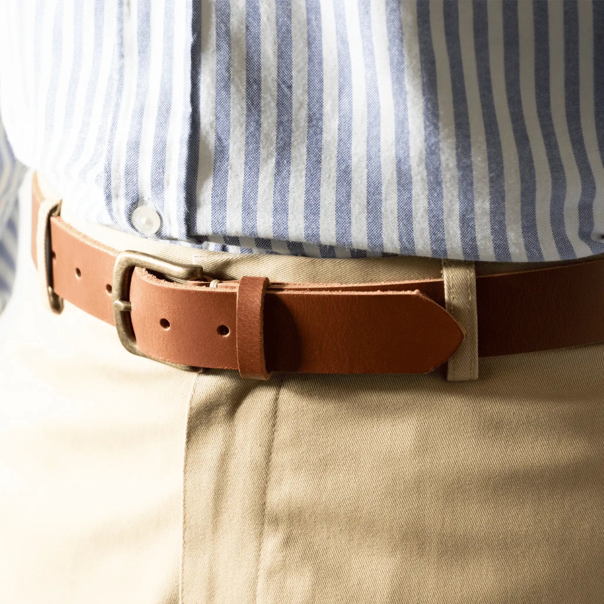 Close-up of a tan leather belt, worn by a man with smart-casual work attire. Made in New Zealand from genuine leather.