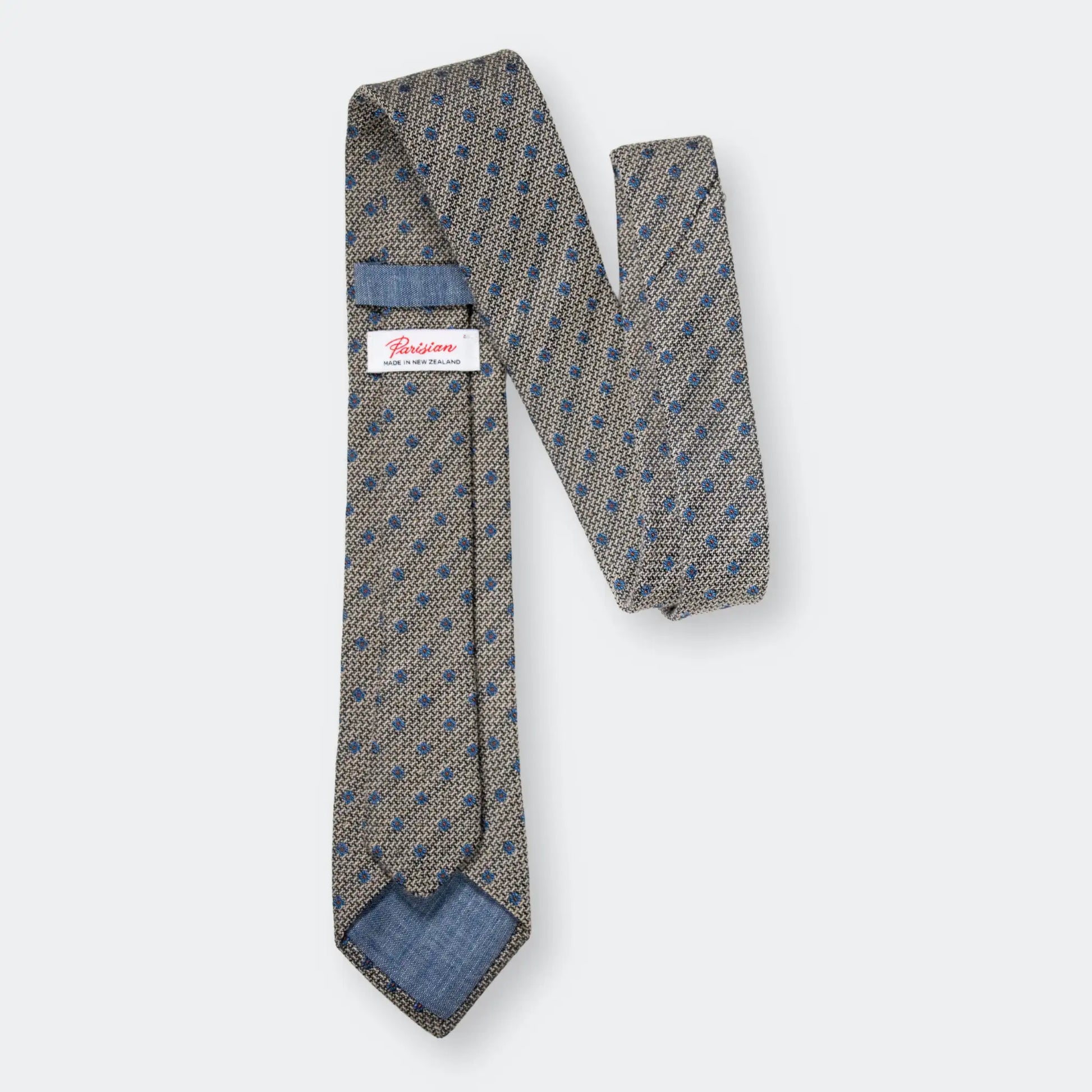 Back of Hessian texture tie with blue flower design featuring 'Parisian Made in New Zealand' woven label and showcasing textured weave.