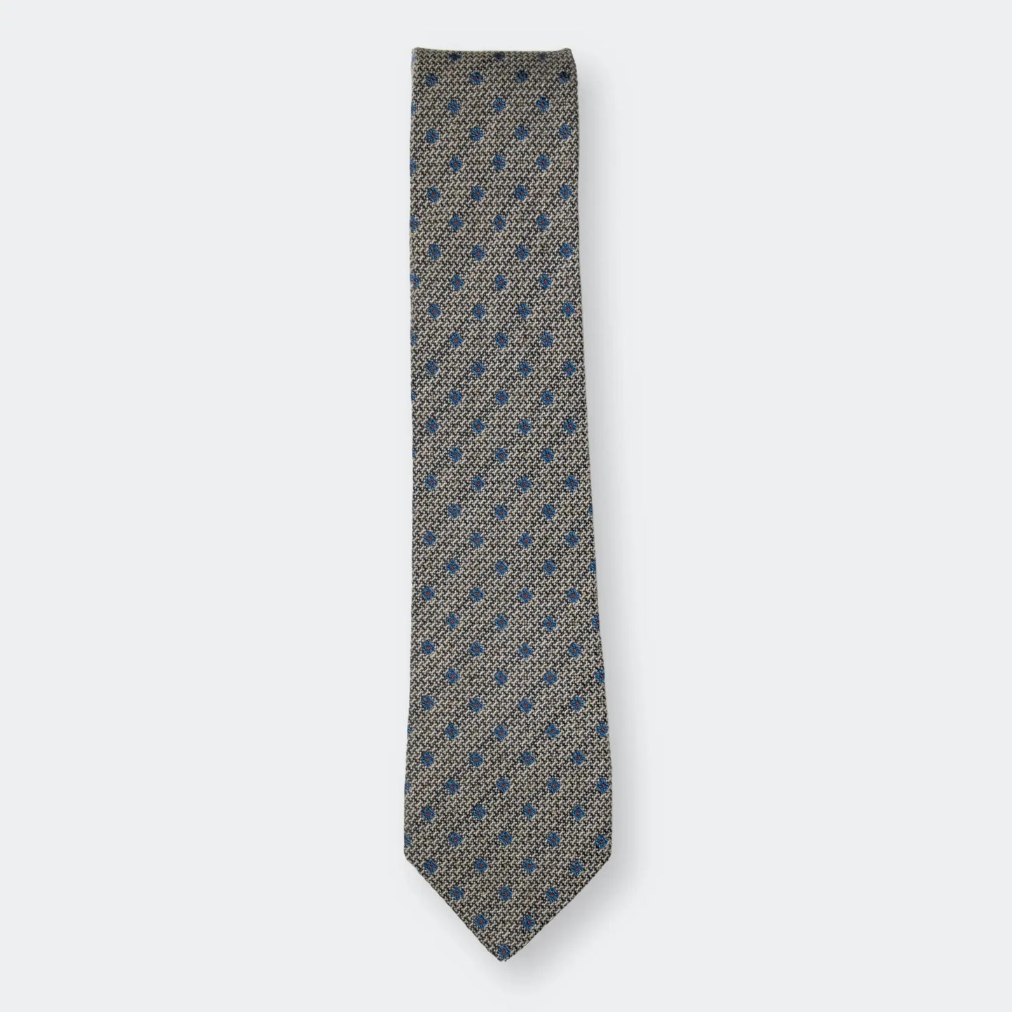 The Hessian textured woven tie with simple blue flower design, folded neatly on a white background highlighting quality material and design.