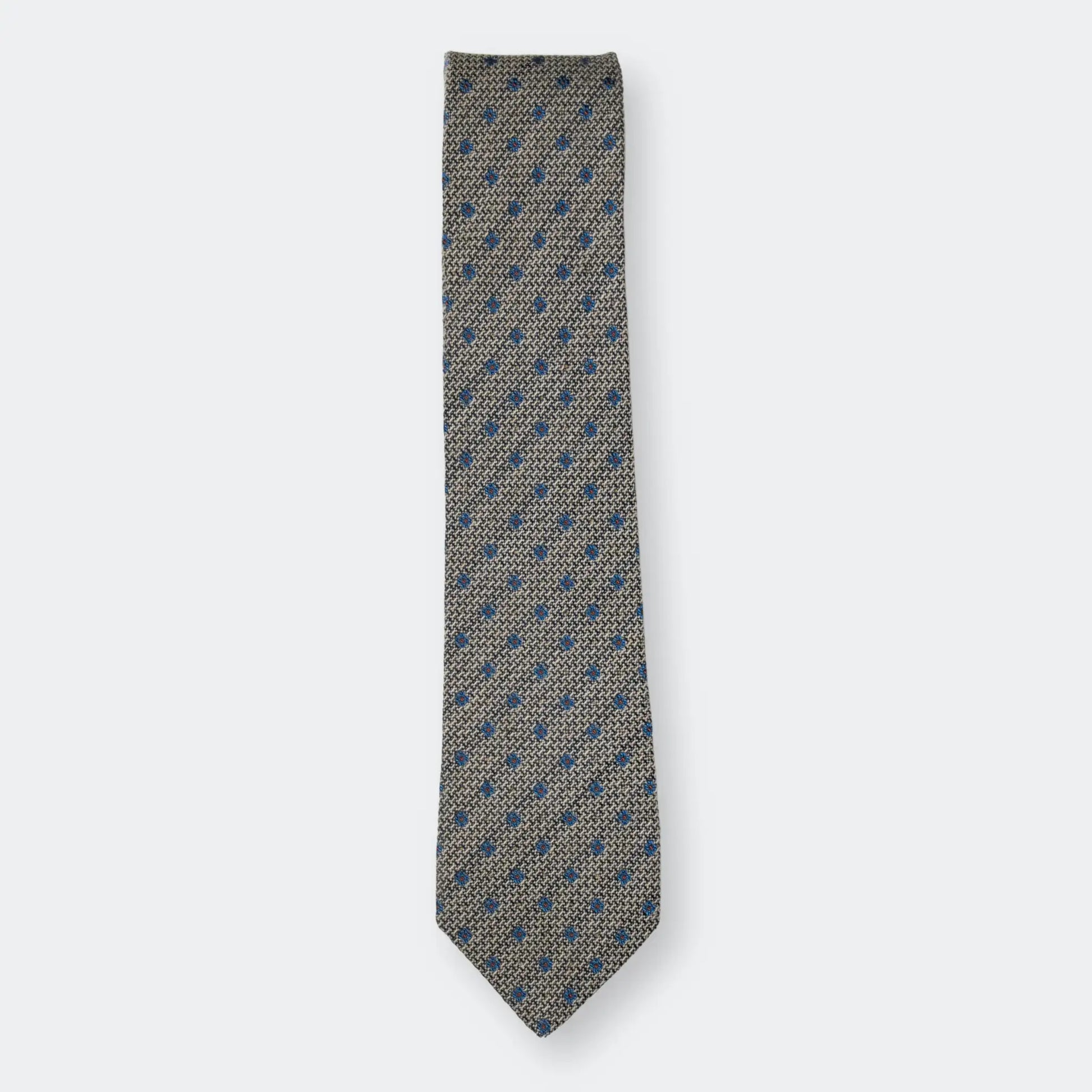 The Hessian textured woven tie with simple blue flower design, folded neatly on a white background highlighting quality material and design.