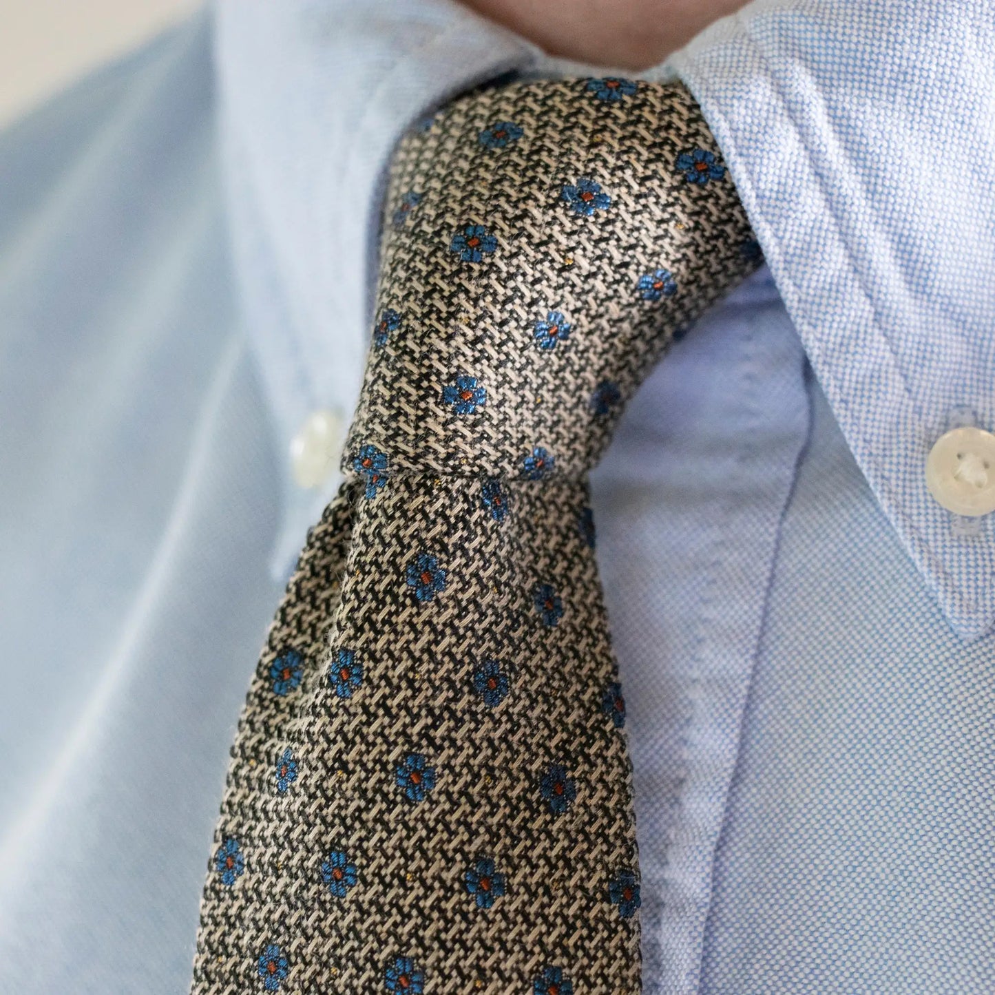 Close-up of hessian textured tie with blue flower pattern, showcasing its simplistic design and premium craftsmanship—quality men's accessory.