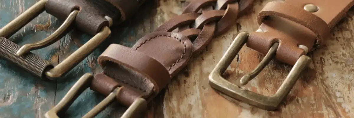 Three leather belts in different shades of brown with detailed buckles