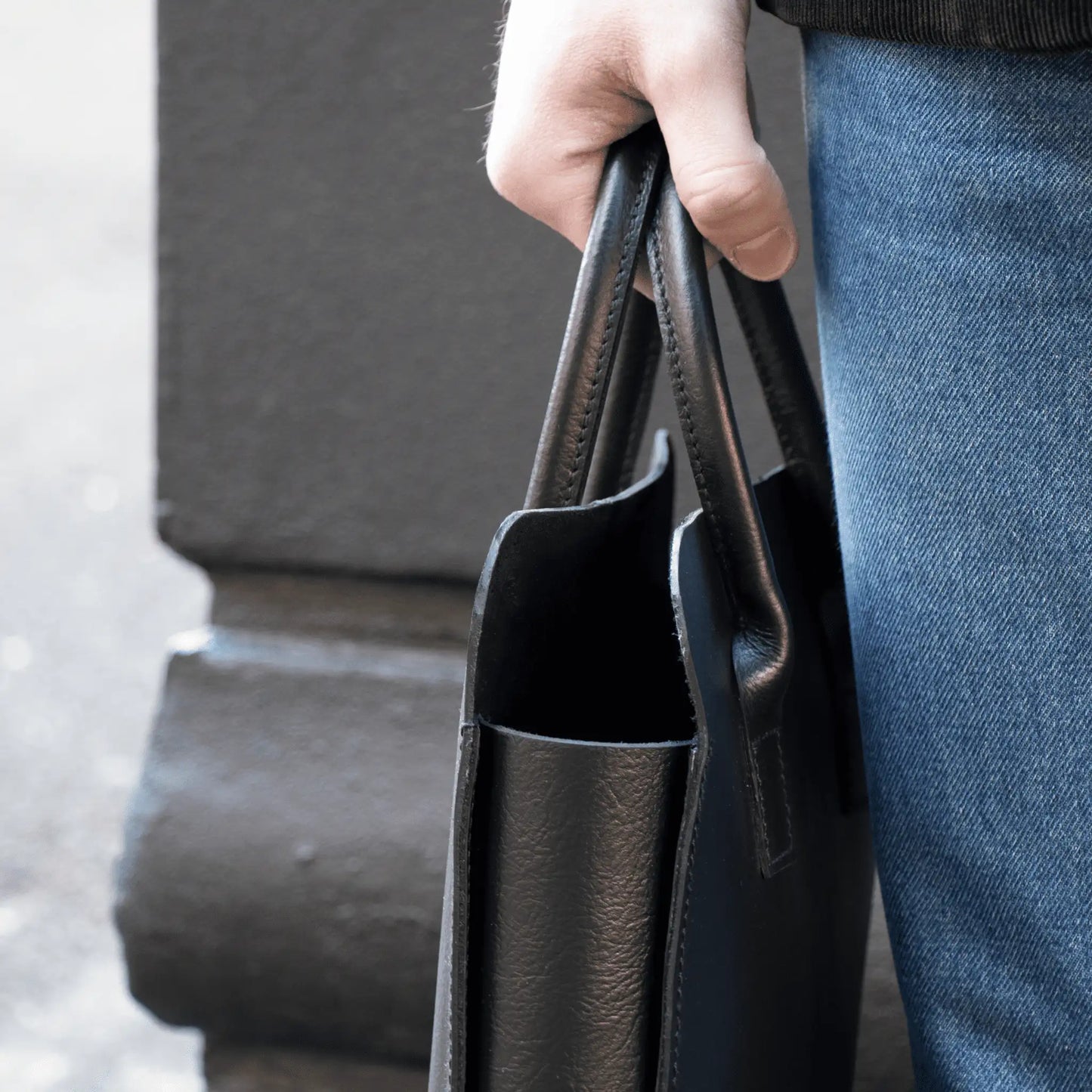 Close-up of hand holding crafted Black Leather Business Tote, highlighting premium leather and quality New Zealand craftsmanship.