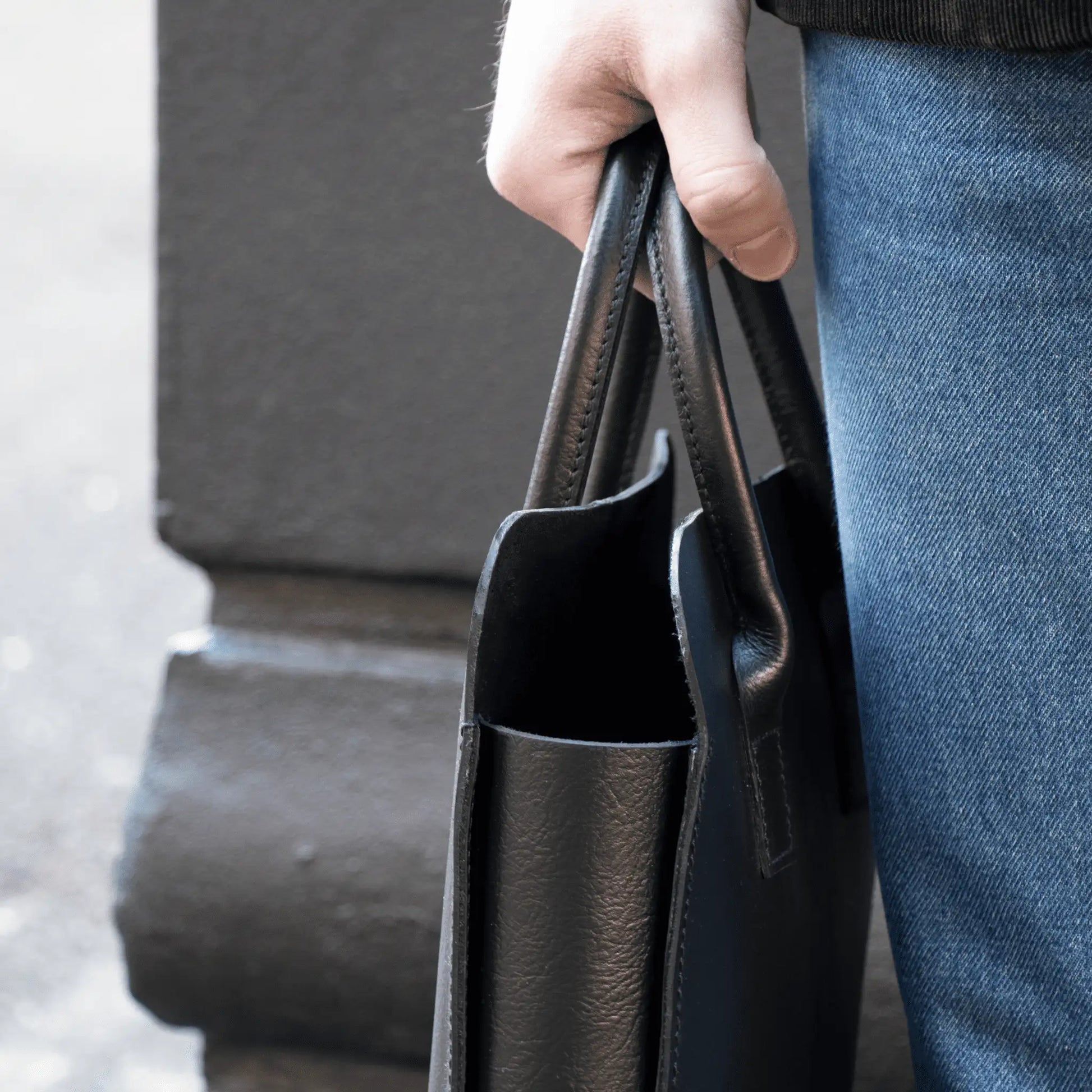 Close-up of hand holding crafted Black Leather Business Tote, highlighting premium leather and quality New Zealand craftsmanship.