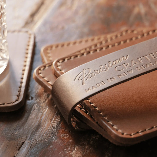 Close up of tan leather coasters showcasing premium quality leather and delicate stitching with a stylish embossed logo.