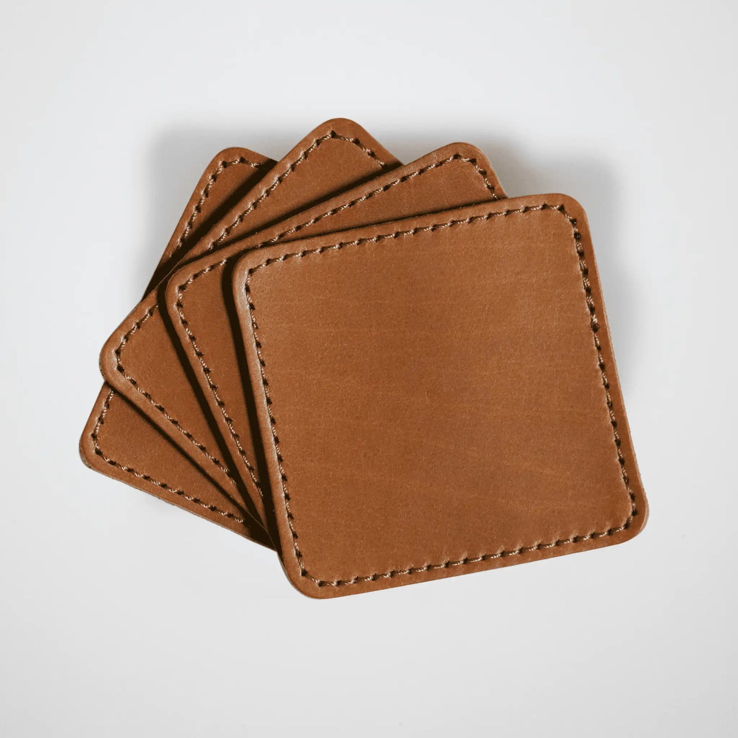Set of four Stitched Leather Coasters in tan on a clean white background showcasing premium craftsmanship and premium quality leather.