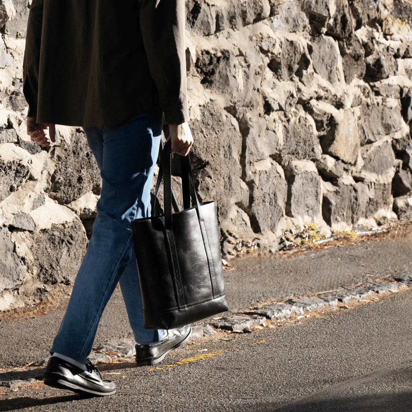 Man walking with Black Leather Everyday Tote—expertly designed and made in New Zealand, blending functional elegance with rich leather texture.