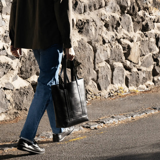 Man walking with Black Leather Everyday Tote—expertly designed and made in New Zealand, blending functional elegance with rich leather texture.