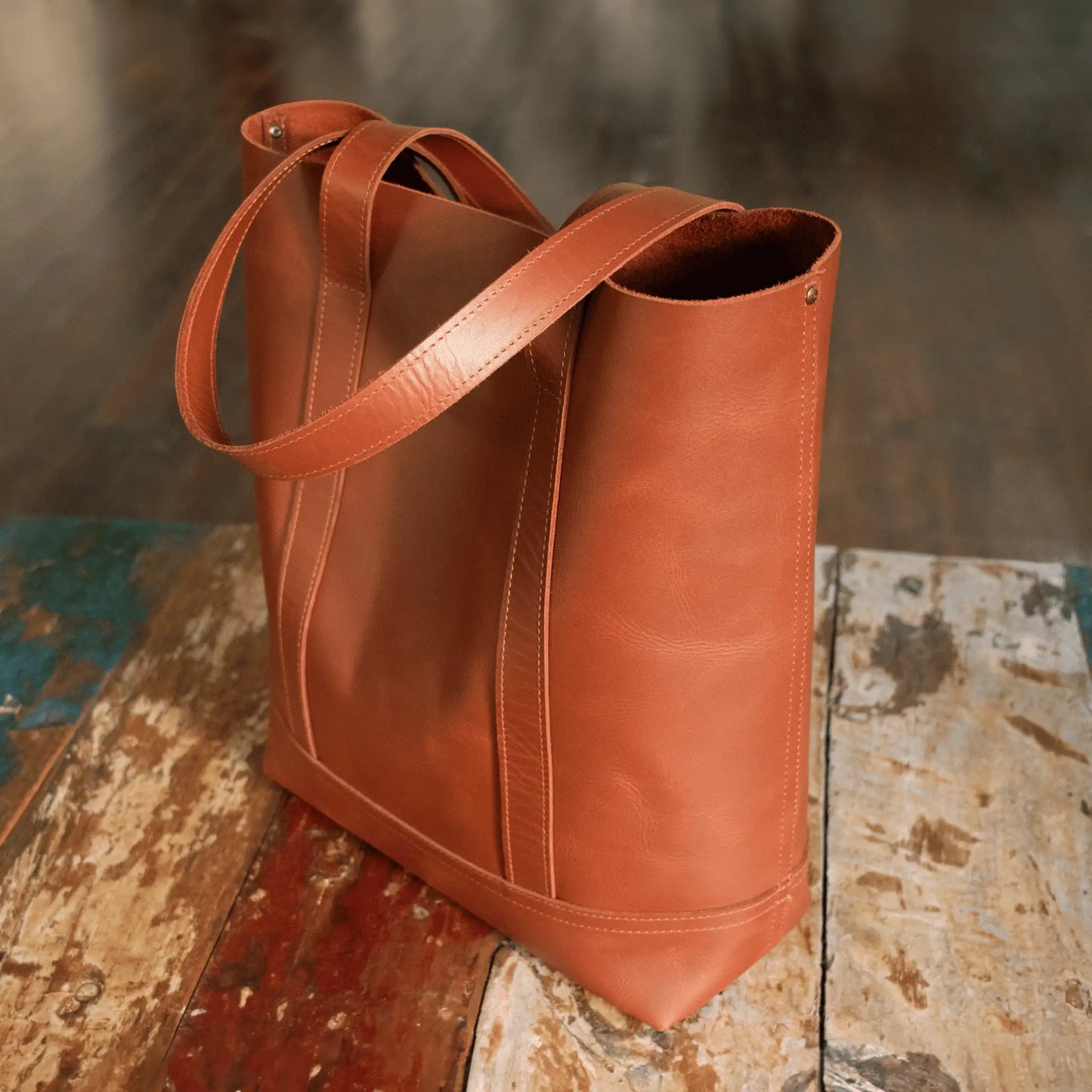 Tan Leather Everyday Tote on rustic wooden table, capturing timeless elegance and refined Parisian craftsmanship.
