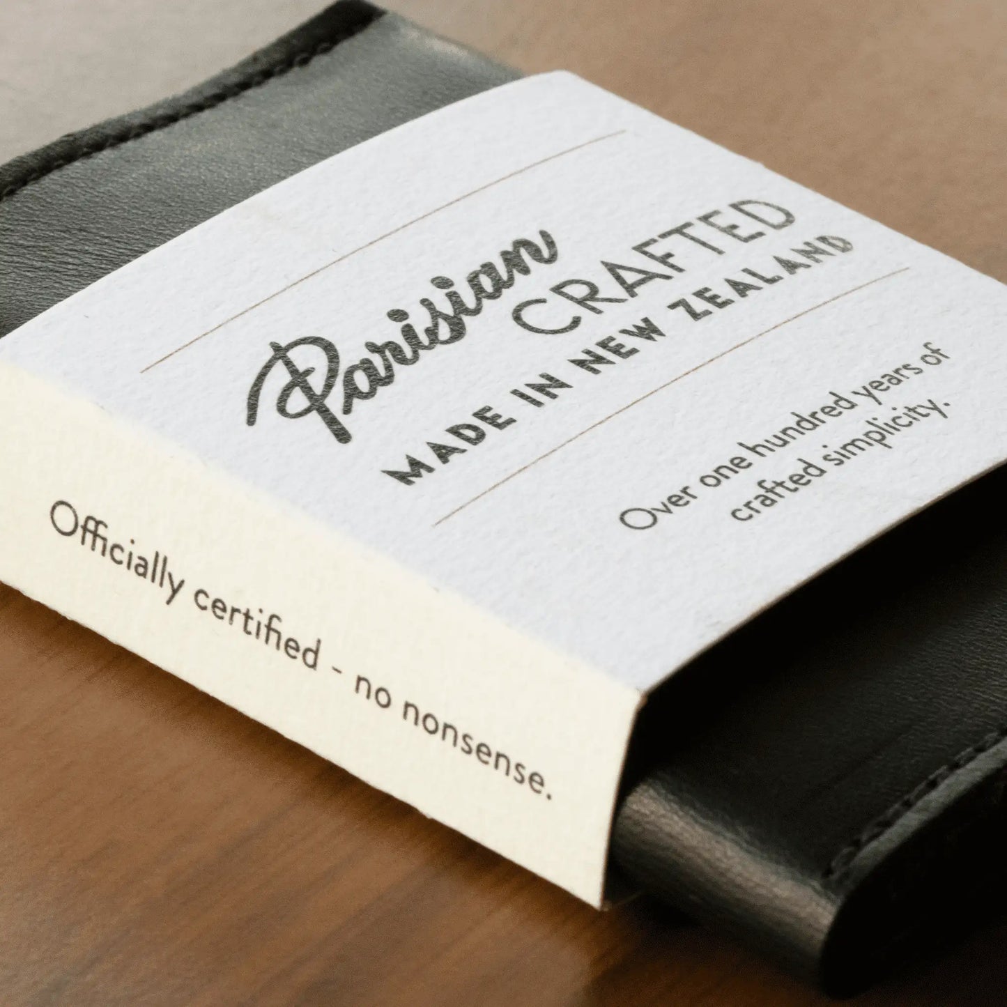 Close-up of black leather folded card wallet wrapped in white card packaging, highlighting sleek design and quality craftsmanship.