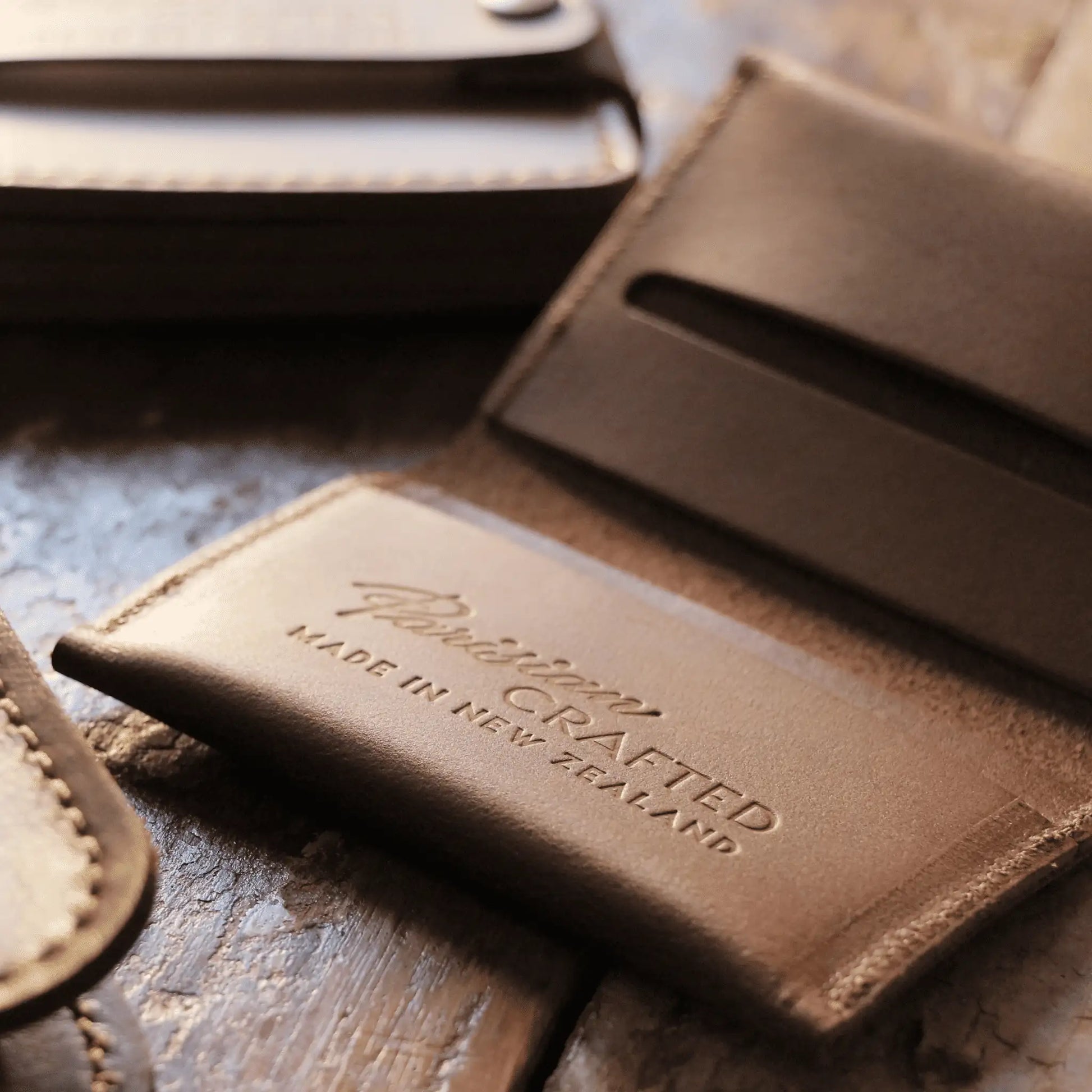 Close-up of the embossed "Parisian Crafted Made in New Zealand" text on the inside of a tan leather folded card wallet.
