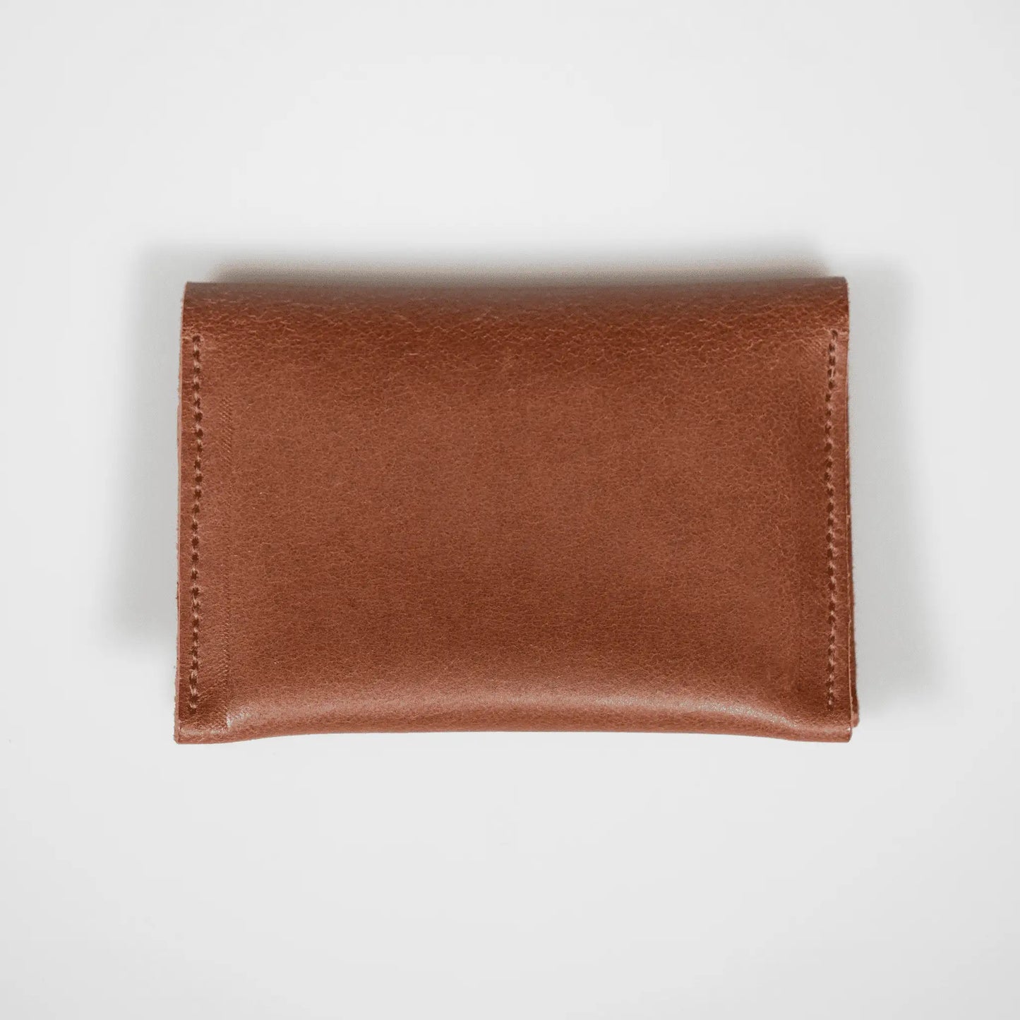 Closed tan leather folded card wallet on a white background, showcasing premium leather and sleek, minimalist design.