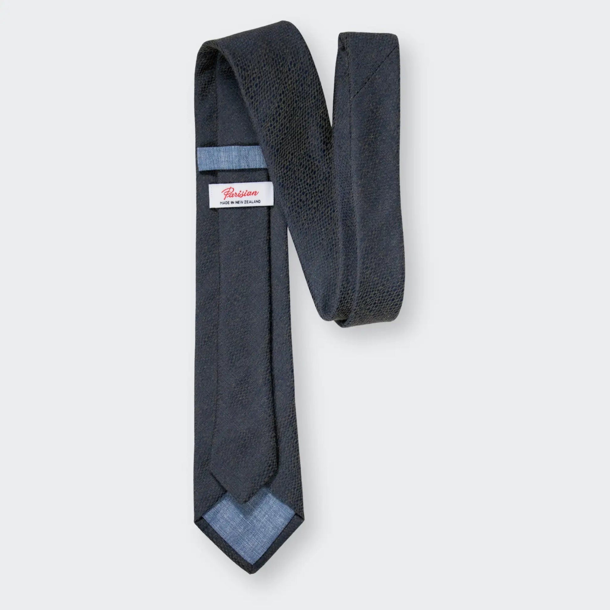 Back of olive green and navy blue cotton-blend jacquard tie, showing the 'Parisian Made in New Zealand' woven label.