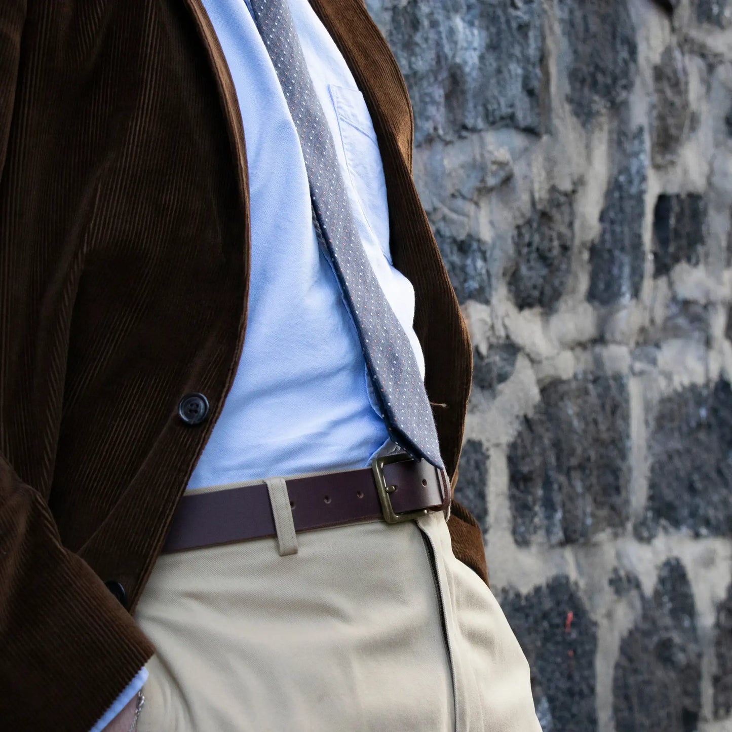 Denim blue tie with white and rust coloured pin-dot pattern paired with a blue shirt and brown jacket, showcasing smart-casual work-wear for men.