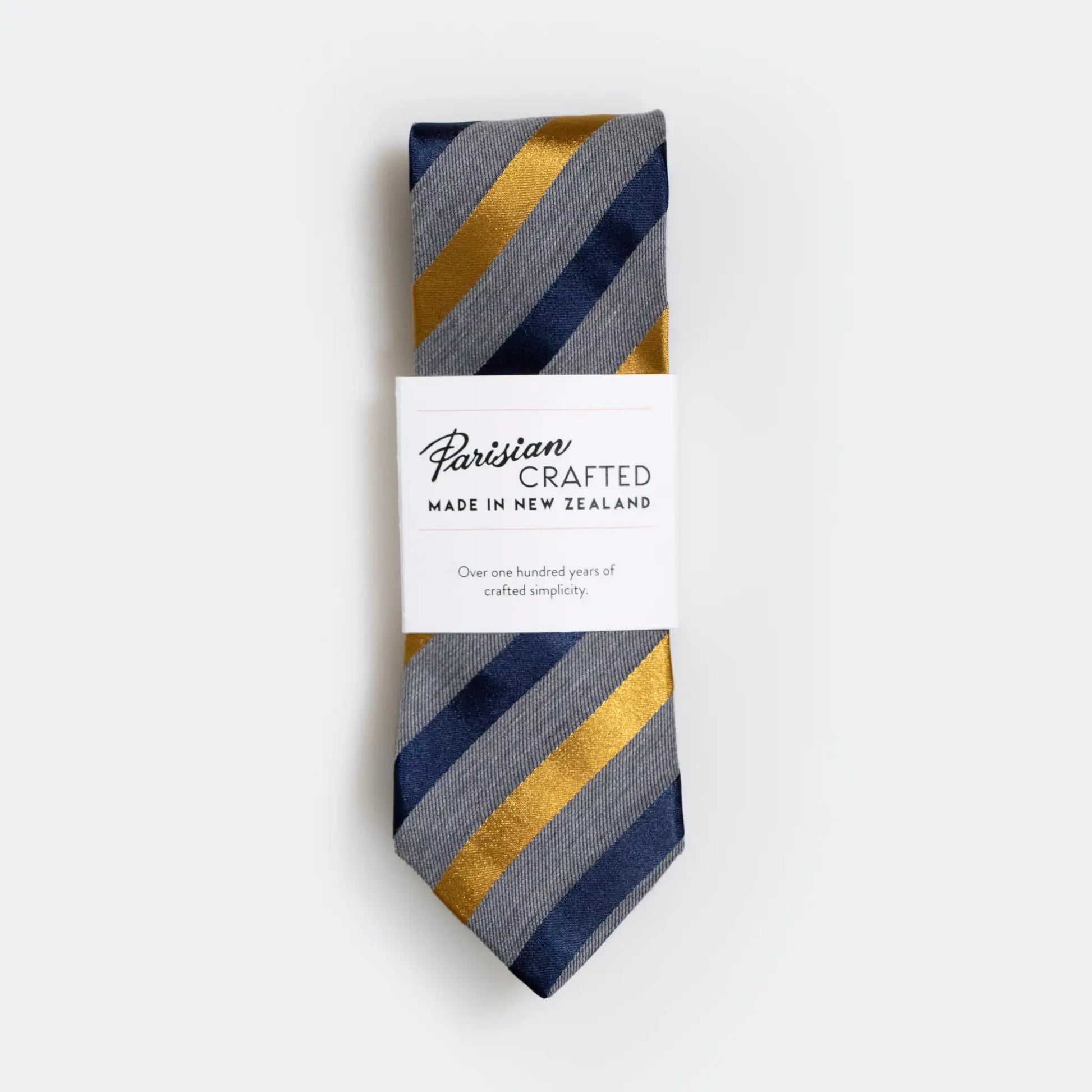 Grey marle tie with stylish navy and gold satin stripes, folded and packaged in a simple white sleeve with Parisian Crafted logo.