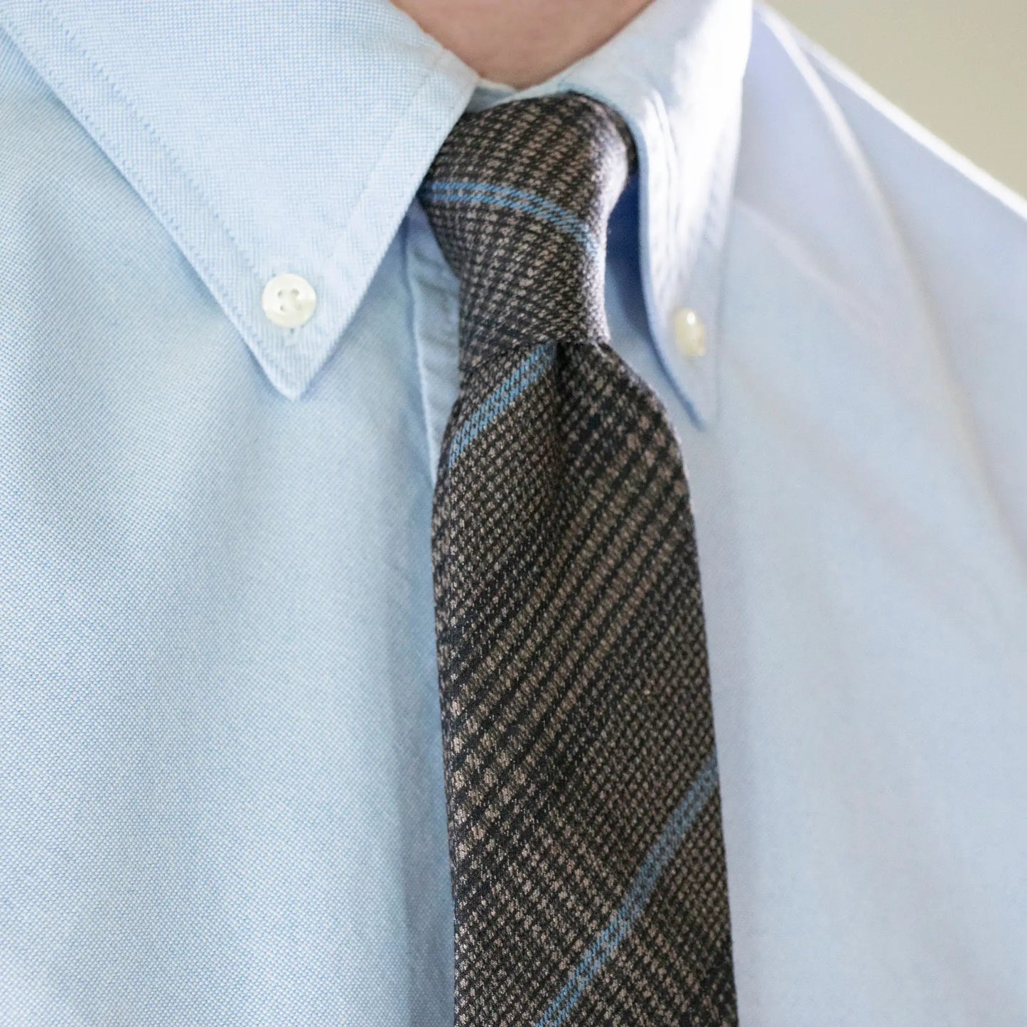 Close-up of slate blue checkered necktie paired with light blue shirt - crafted in New Zealand.