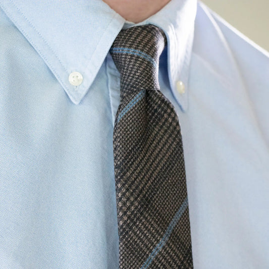Close-up of slate blue checkered necktie paired with light blue shirt - crafted in New Zealand.