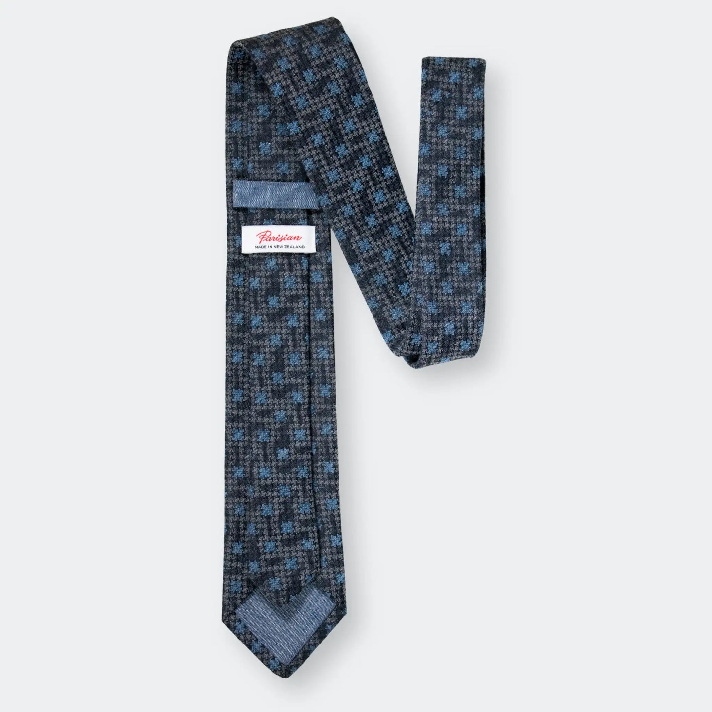 Back of the slate blue Houndstooth design tie showing "Parisian Made in New Zealand" woven label, emphasising refined design and materials.