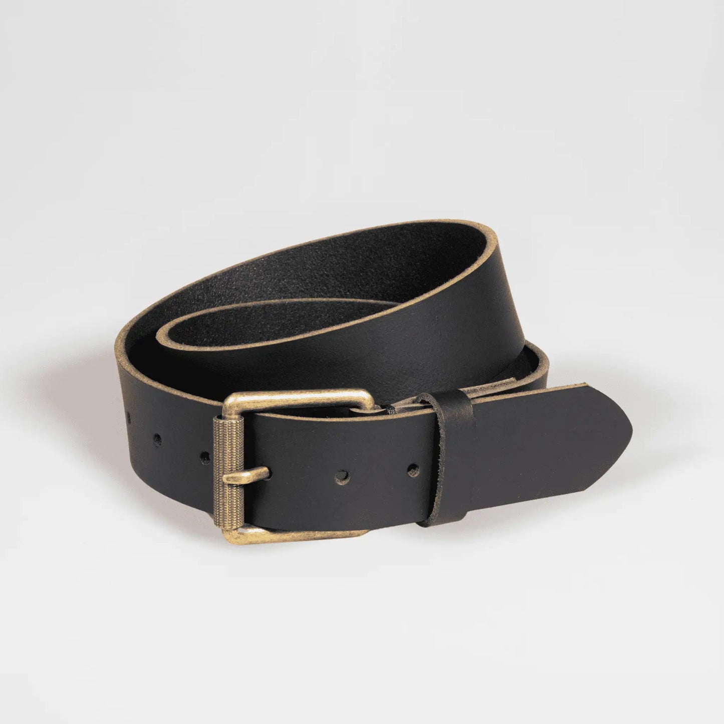 Black wide leather work belt rolled up on white surface. Expertly crafted New Zealand men's accessory with functional design and thick leather texture.
