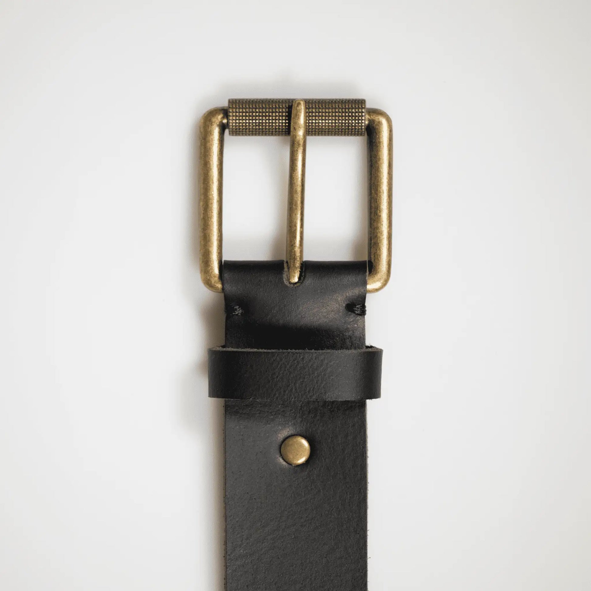 Close-up of detailed brass buckle on black genuine leather belt, crafted locally in New Zealand.