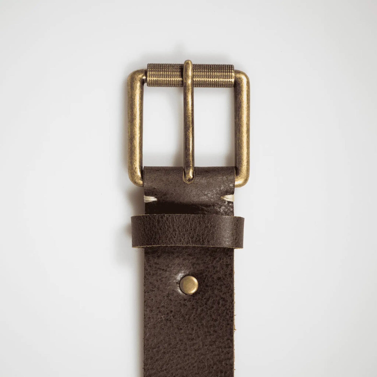 Close-up of brass hardware on brown hand-woven leather belt, highlighting refined stitching and quality leather—small batch, made to last.