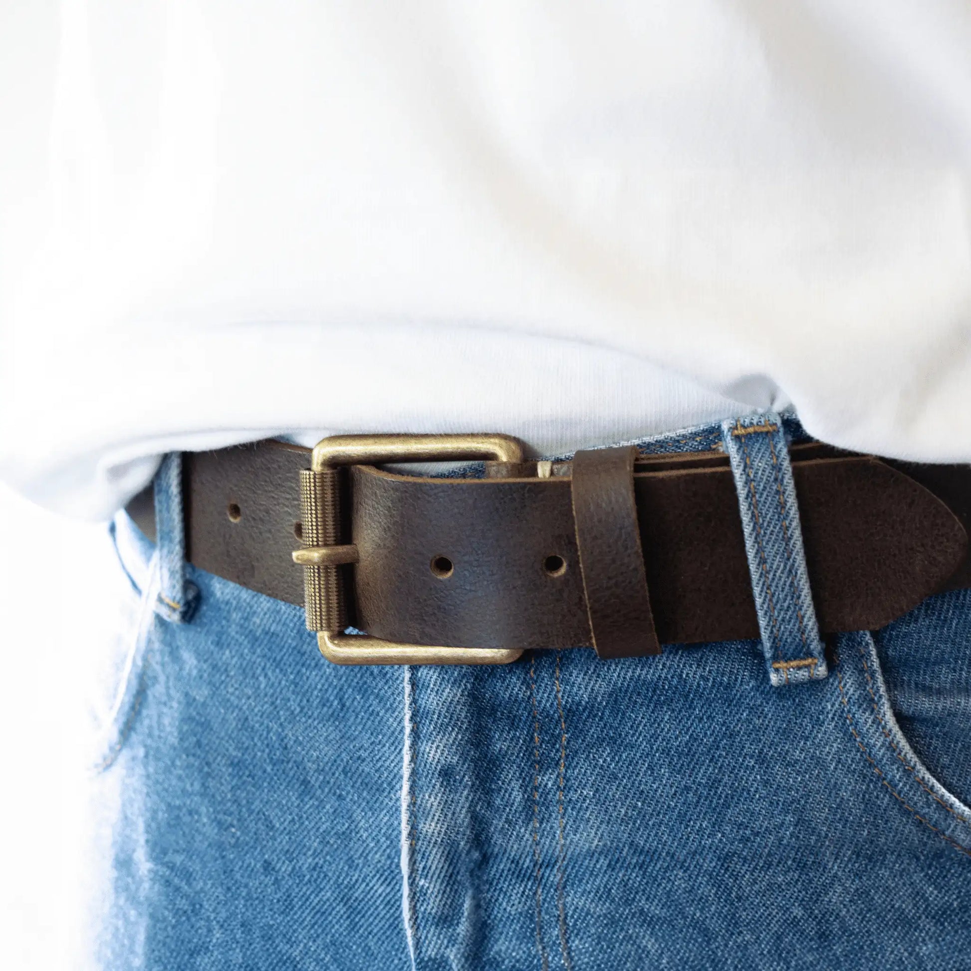 Close-up of men's brown leather work belt showcasing detailed brass buckle and rustic genuine leather.
