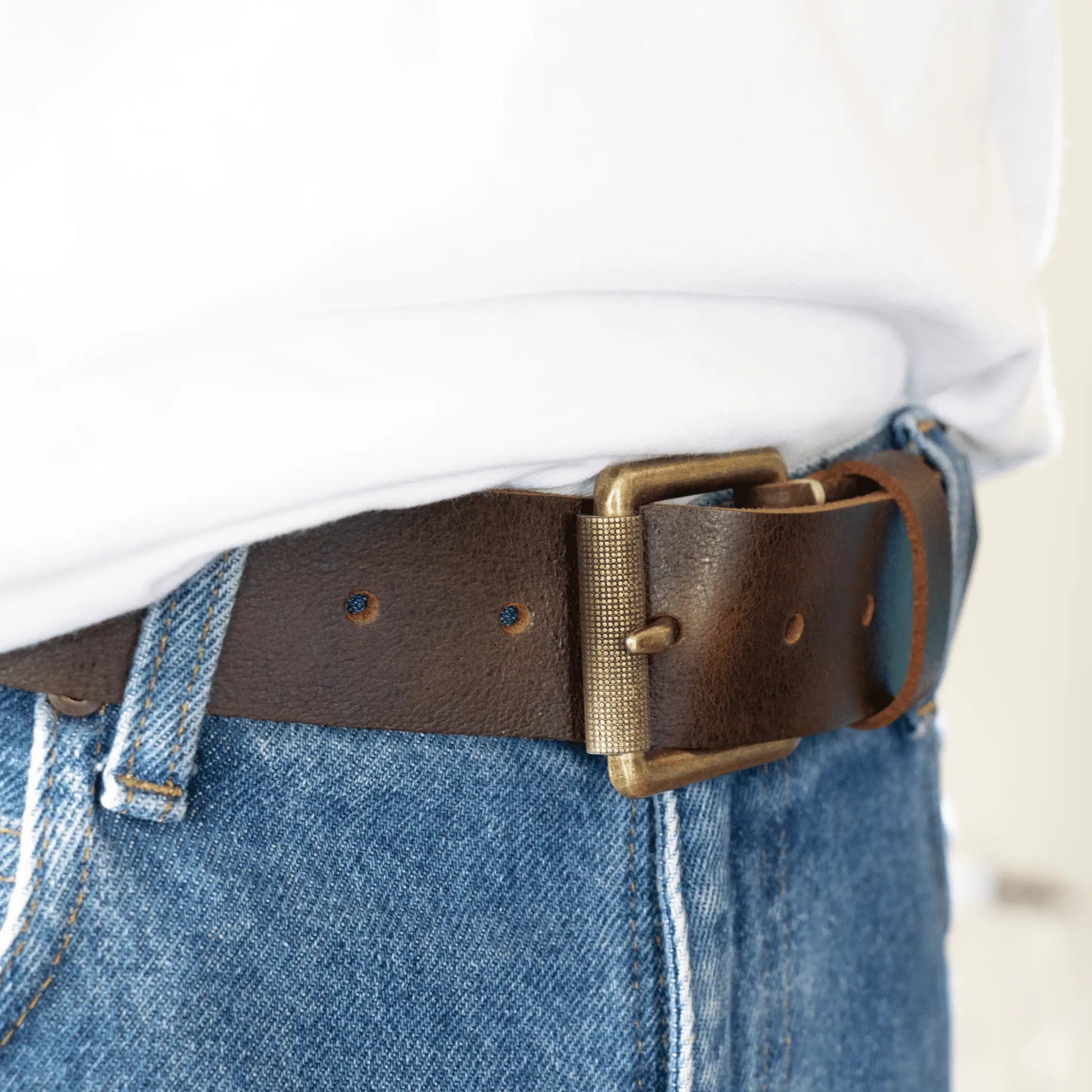 Close-up of wide brown leather men's belt paired with jeans and a white t-shirt. Everyday men's accessory made locally in New Zealand.