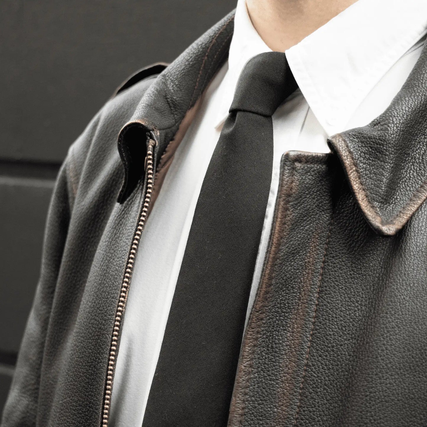 Premium leather jacket paired with crisp white shirt and pure wool black tie, showcasing refined Parisian craftsmanship