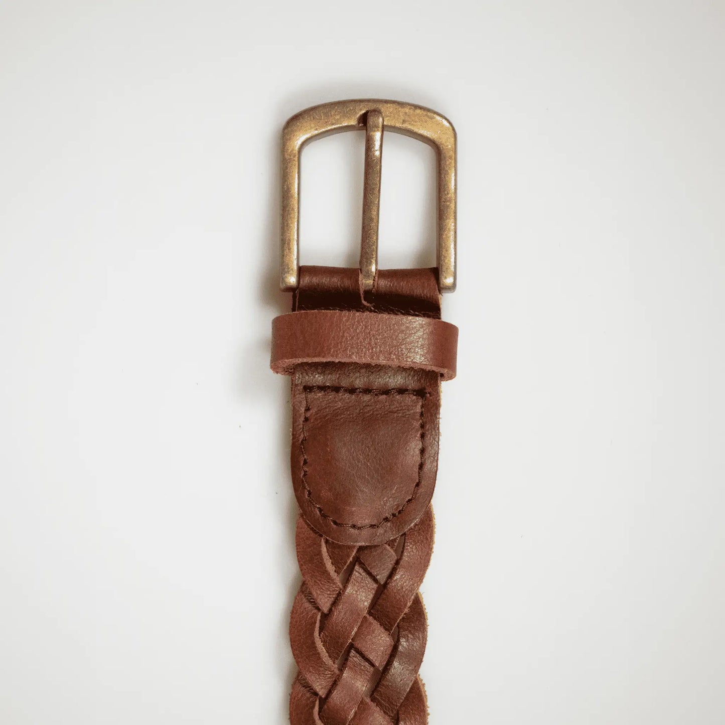 Close-up of brass hardware on brown hand-woven leather belt, highlighting refined stitching and quality leather—small batch, made to last.