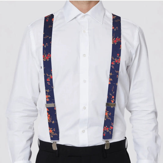 Person wearing a white shirt with navy and red Liberty London suspenders on a plain background