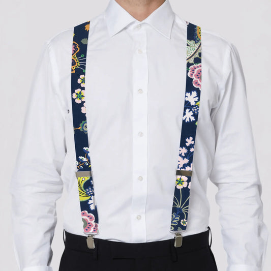 Person wearing a white shirt with floral-patterned Liberty London suspenders on a plain background