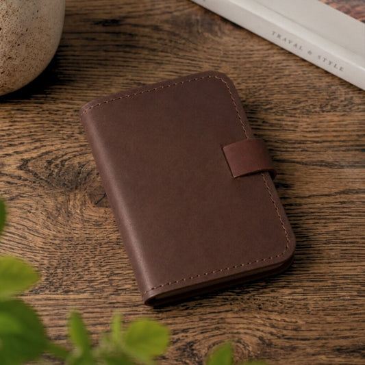 Brown leather notebook on a wooden surface with a plant in the foreground