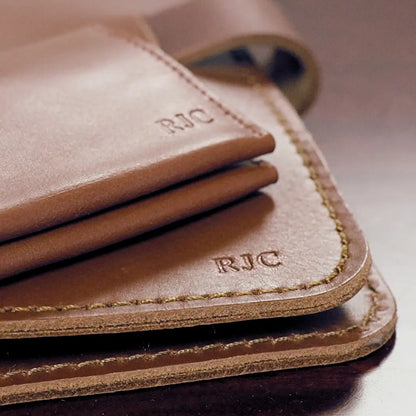 Custom embossing of initials on a tan leather wallet and notebook