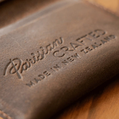 Close-up of the "Parisian Crafted Made in New Zealand" text inside a brown leather folded card wallet, showcasing fine leather quality.