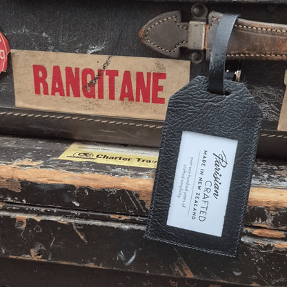 Vintage suitcase with a black leather luggage tag and 'Rangitane' shipping sticker