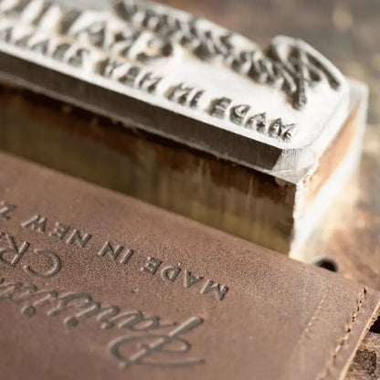 Parisian Crafted Made in New Zealand logo stamp and logo on brown leather wallet, close-up