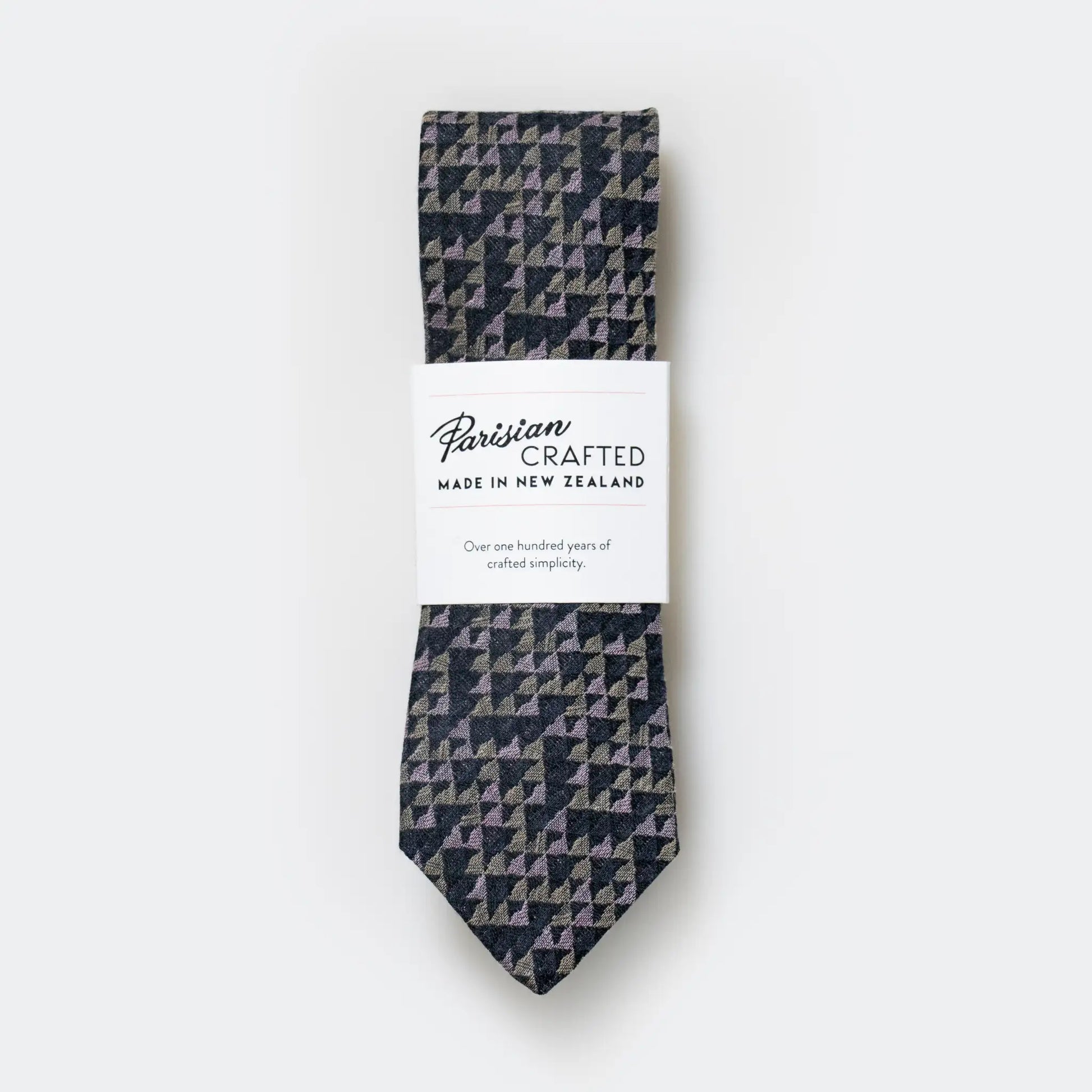 Geometric patterned tie in sage, pink and charcoal, folded into Parisian Crafted's signature white packaging - quality craftsmanship Made in NZ.